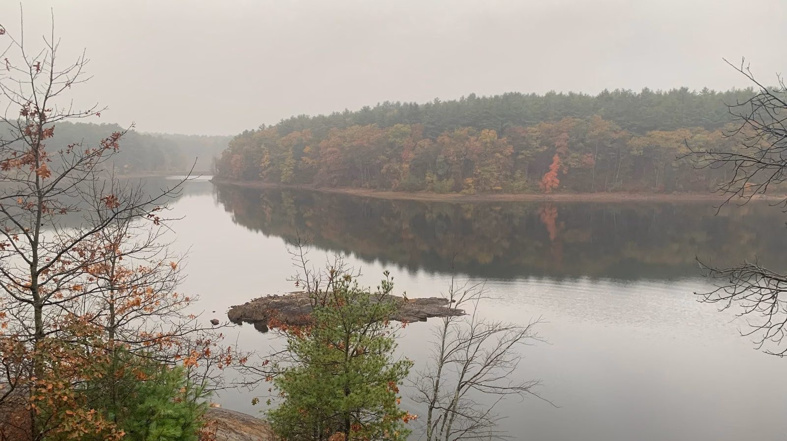 Foggy reservoir with fall color and a small rocky island, seen from a ledge, Middlesex Fells, Stoneham